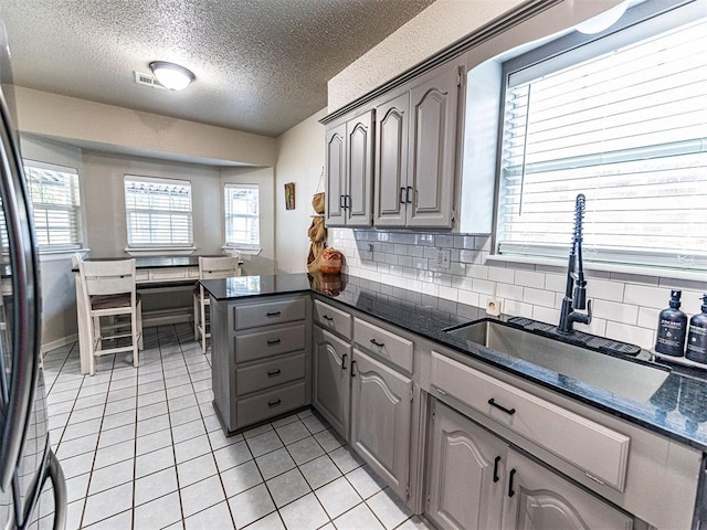 kitchen featuring sink, gray cabinets, stainless steel fridge, backsplash, and light tile patterned flooring