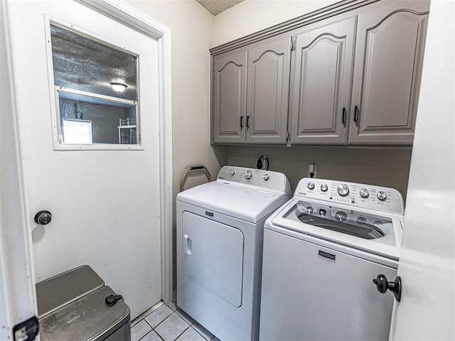 clothes washing area featuring cabinets, light tile patterned floors, and washer and dryer