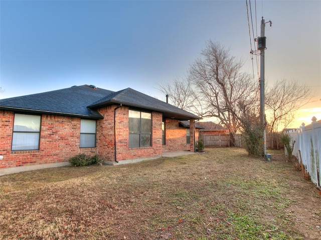 property exterior at dusk featuring a yard