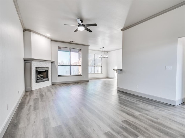 unfurnished living room featuring crown molding, ceiling fan with notable chandelier, and light wood-type flooring