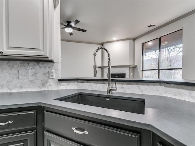 kitchen featuring tasteful backsplash, crown molding, sink, and white cabinets