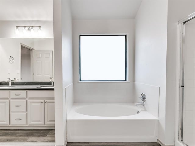 bathroom featuring vanity, wood-type flooring, and plus walk in shower