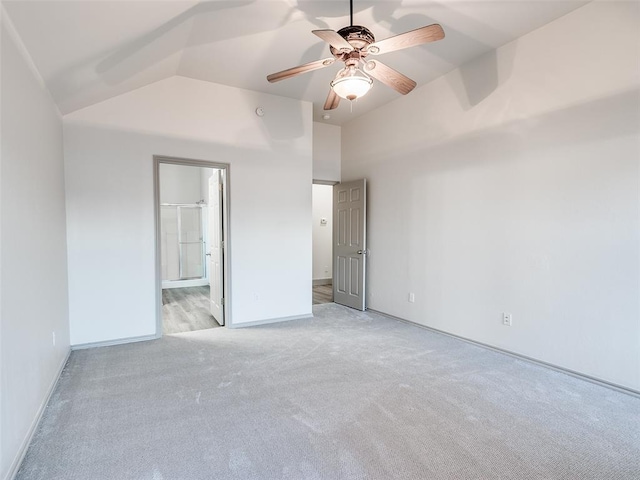 unfurnished bedroom featuring lofted ceiling, light colored carpet, connected bathroom, and ceiling fan