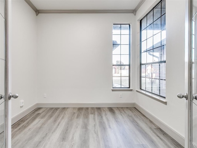 empty room with crown molding, light hardwood / wood-style flooring, and french doors