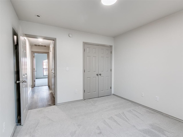 unfurnished bedroom featuring light colored carpet and a closet