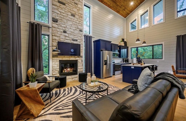 living room with wood ceiling, a fireplace, high vaulted ceiling, and light hardwood / wood-style flooring