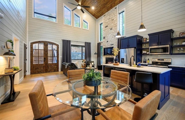 dining area with a stone fireplace, sink, light hardwood / wood-style flooring, and french doors