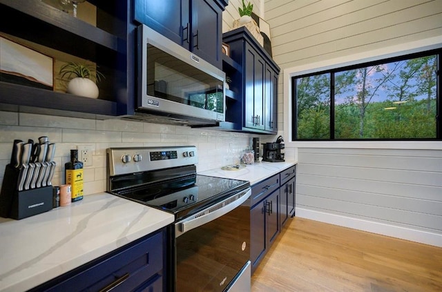 kitchen with blue cabinets, appliances with stainless steel finishes, backsplash, and light hardwood / wood-style flooring