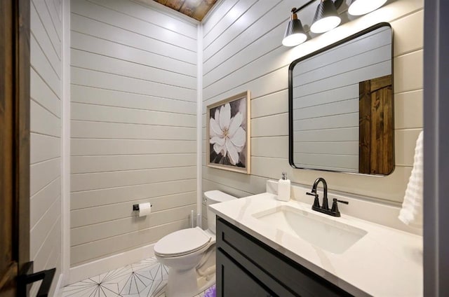 bathroom with vanity, wooden walls, and toilet