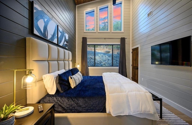 bedroom with a towering ceiling and wooden walls