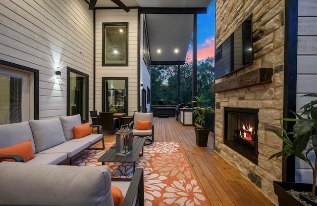 deck at dusk with an outdoor living space with a fireplace