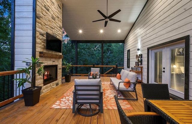 wooden terrace featuring ceiling fan and an outdoor living space with a fireplace