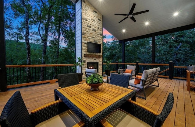 wooden terrace featuring ceiling fan and an outdoor living space with a fireplace