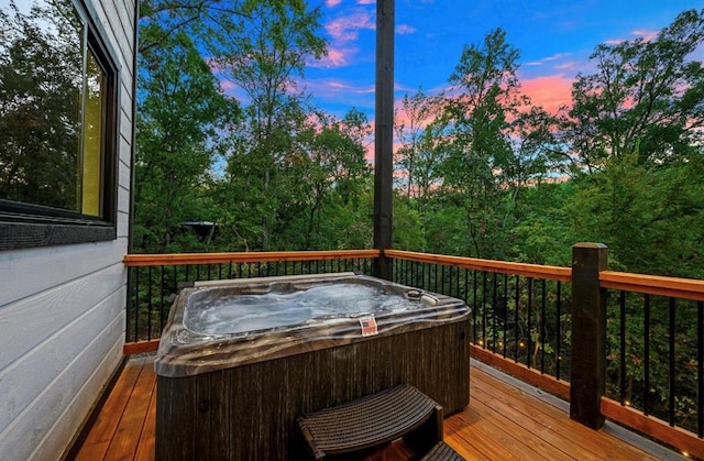 deck at dusk featuring a hot tub