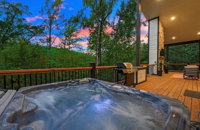 deck at dusk featuring an outdoor hot tub and area for grilling