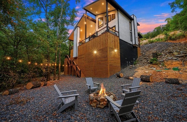 back house at dusk with a balcony and a fire pit