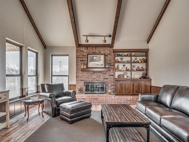 living room with lofted ceiling with beams, a brick fireplace, and hardwood / wood-style floors