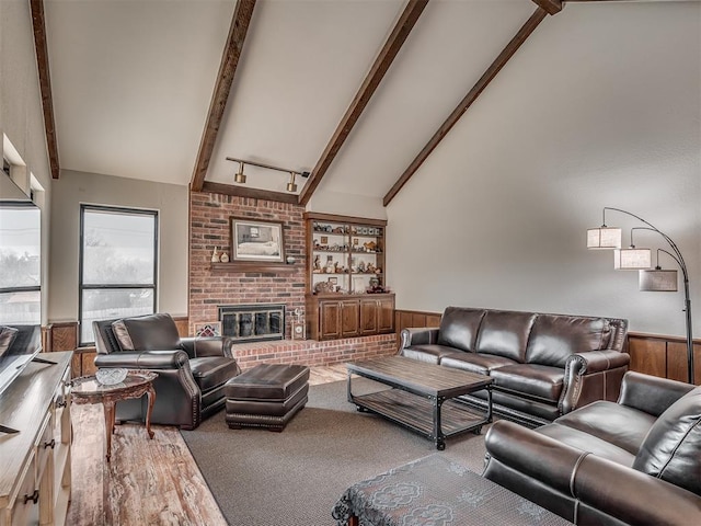 living room featuring beamed ceiling, a fireplace, high vaulted ceiling, and wood walls