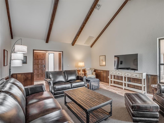 living room featuring carpet floors, high vaulted ceiling, beamed ceiling, and wood walls