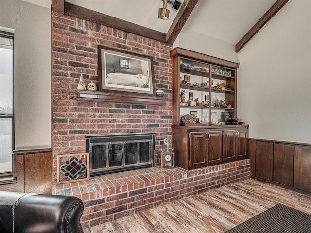 bar with wood walls, dark brown cabinets, a brick fireplace, light wood-type flooring, and beamed ceiling