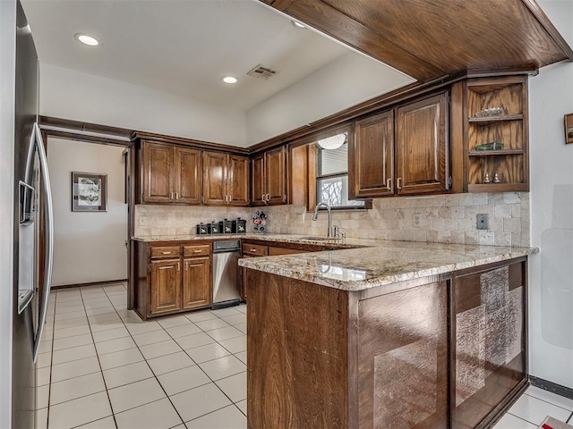 kitchen with light tile patterned floors, stainless steel refrigerator with ice dispenser, light stone counters, tasteful backsplash, and kitchen peninsula