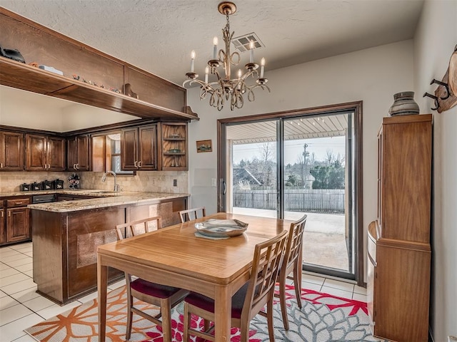 tiled dining area featuring a chandelier, sink, and a textured ceiling