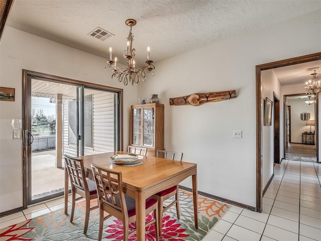 dining area with a chandelier, a textured ceiling, and light tile patterned floors