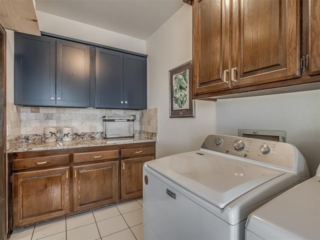 washroom with cabinets, washing machine and dryer, and light tile patterned flooring