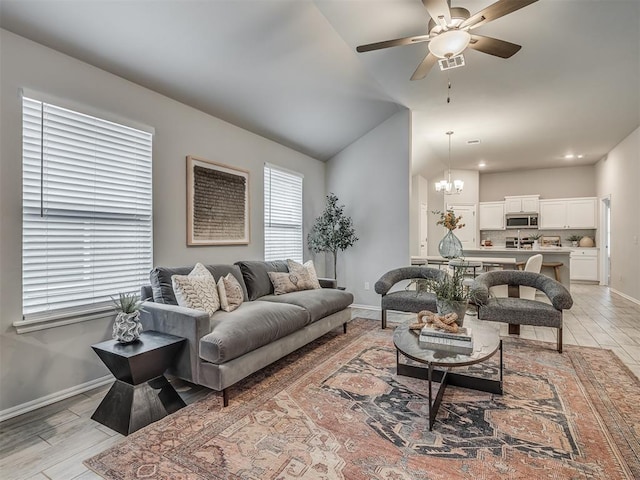 living room featuring vaulted ceiling and ceiling fan with notable chandelier