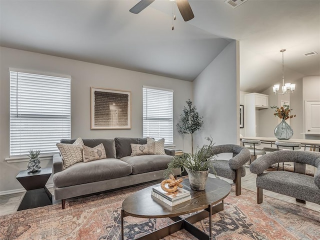 living room featuring vaulted ceiling and ceiling fan with notable chandelier