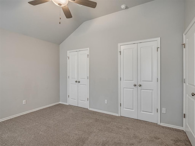 unfurnished bedroom with ceiling fan, lofted ceiling, carpet floors, and two closets