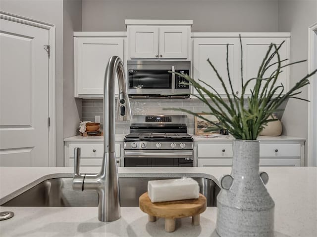 kitchen with tasteful backsplash, appliances with stainless steel finishes, and white cabinets