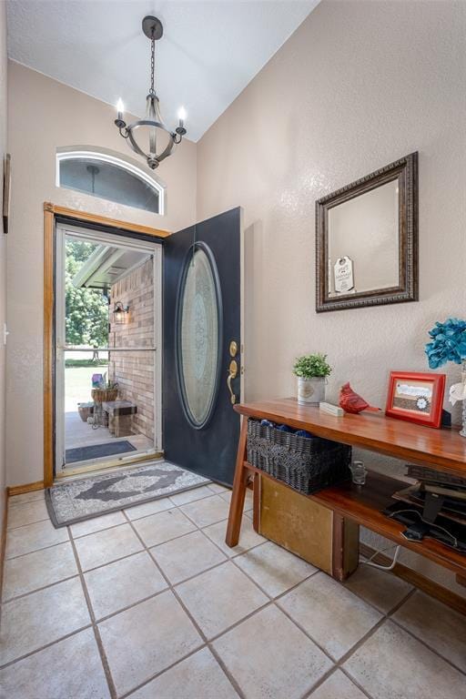 tiled entryway with a notable chandelier