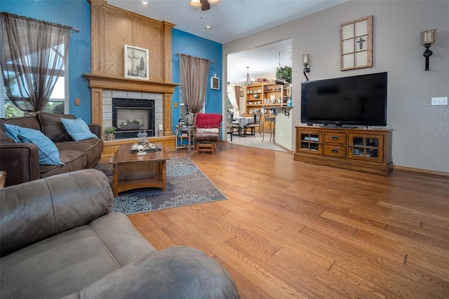 living room featuring hardwood / wood-style flooring, a fireplace, and ceiling fan with notable chandelier