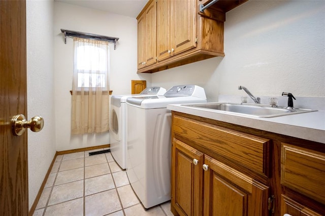 laundry area featuring separate washer and dryer, sink, light tile patterned floors, and cabinets