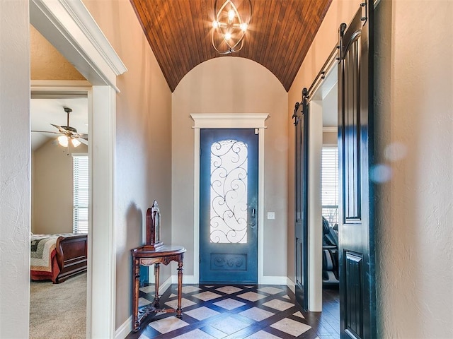 entryway with lofted ceiling, a barn door, ceiling fan with notable chandelier, and plenty of natural light