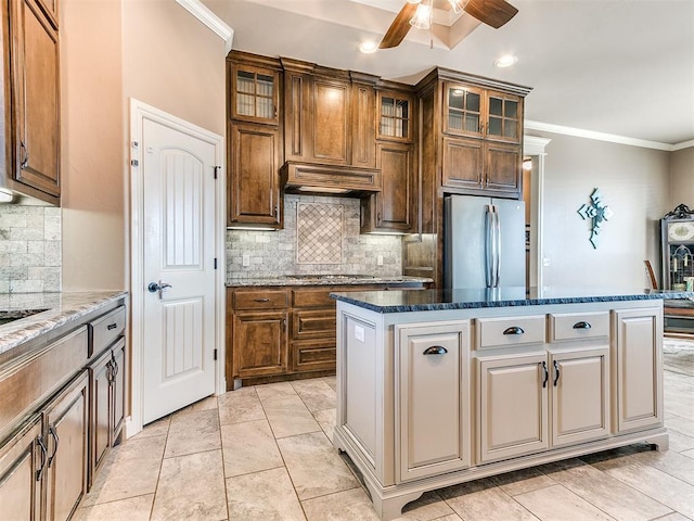 kitchen featuring dark stone countertops, custom range hood, stainless steel refrigerator, and a center island