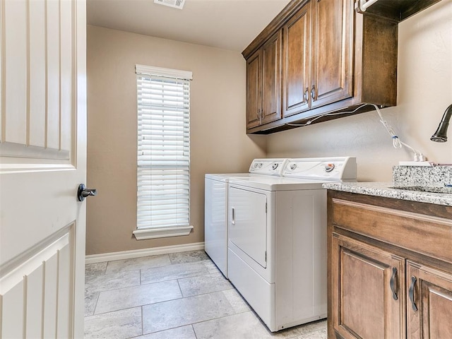 washroom with cabinets, washing machine and dryer, and sink