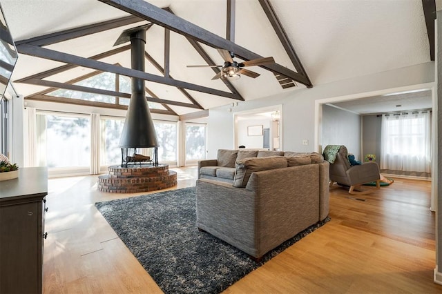 living room featuring beamed ceiling, high vaulted ceiling, hardwood / wood-style floors, and a wood stove