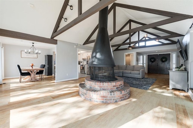 living room featuring beam ceiling, high vaulted ceiling, light hardwood / wood-style floors, ceiling fan with notable chandelier, and a wood stove