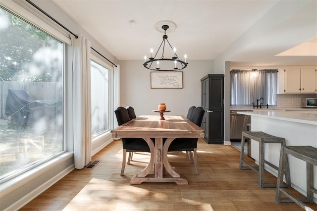 dining space featuring sink, a notable chandelier, and light hardwood / wood-style flooring