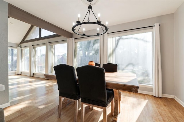 dining space featuring a notable chandelier, lofted ceiling with beams, light hardwood / wood-style floors, and a healthy amount of sunlight