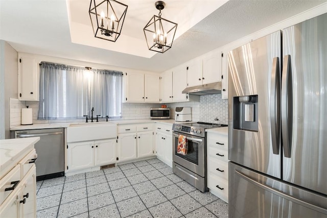 kitchen featuring sink, appliances with stainless steel finishes, decorative backsplash, white cabinets, and decorative light fixtures