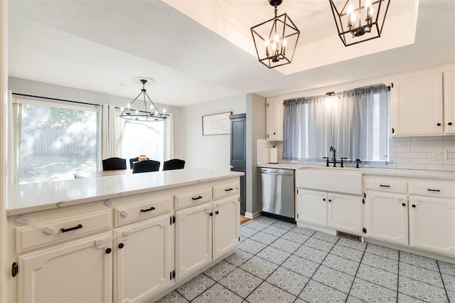 kitchen with hanging light fixtures, decorative backsplash, stainless steel dishwasher, and sink