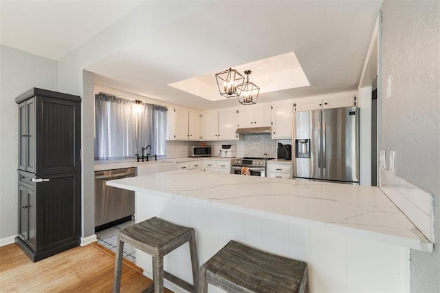 kitchen featuring stainless steel appliances, white cabinetry, light hardwood / wood-style flooring, and kitchen peninsula