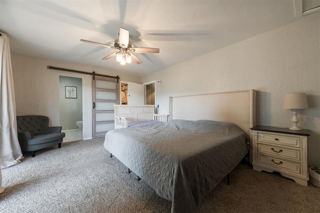 bedroom with light carpet, ensuite bath, a barn door, and ceiling fan