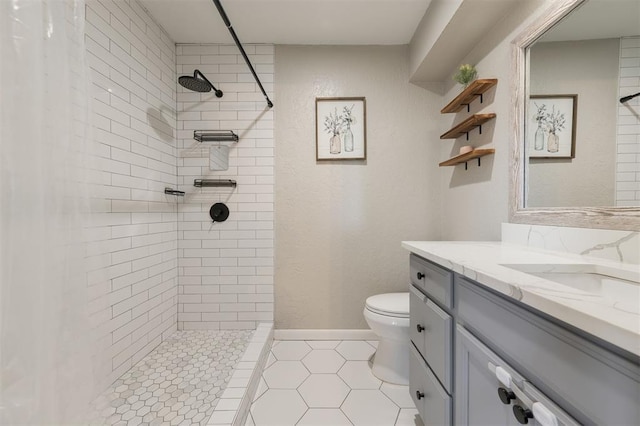 bathroom featuring tiled shower, vanity, toilet, and tile patterned flooring