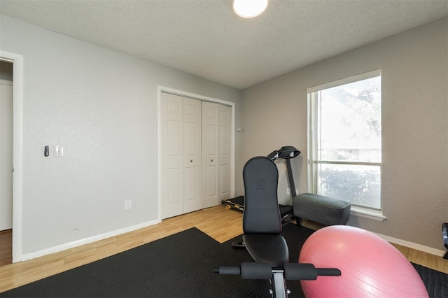 exercise area with light hardwood / wood-style flooring and a textured ceiling