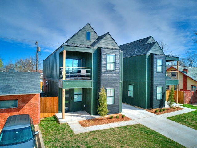 view of front of property featuring a balcony and a front yard