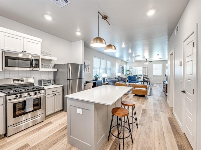 kitchen featuring a center island, light hardwood / wood-style flooring, a kitchen breakfast bar, pendant lighting, and stainless steel appliances